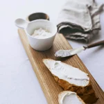 Fetta di pane rustico a basso contenuto di carboidrati con formaggio spalmabile su tagliere in legno