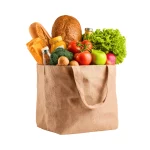 Borsa della spesa in tessuto ecologico piena di prodotti freschi, pane rustico e verdure di stagione.